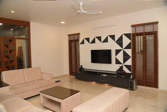 Wooden blinds on living-room windows beside a TV wall